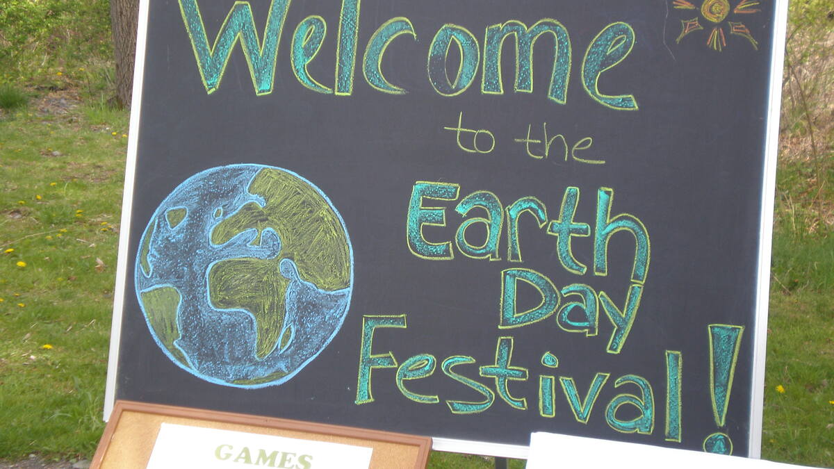 A chalkboard sign with a chalk drawing of the Earth and the words Welcome to the Earth Day Festival