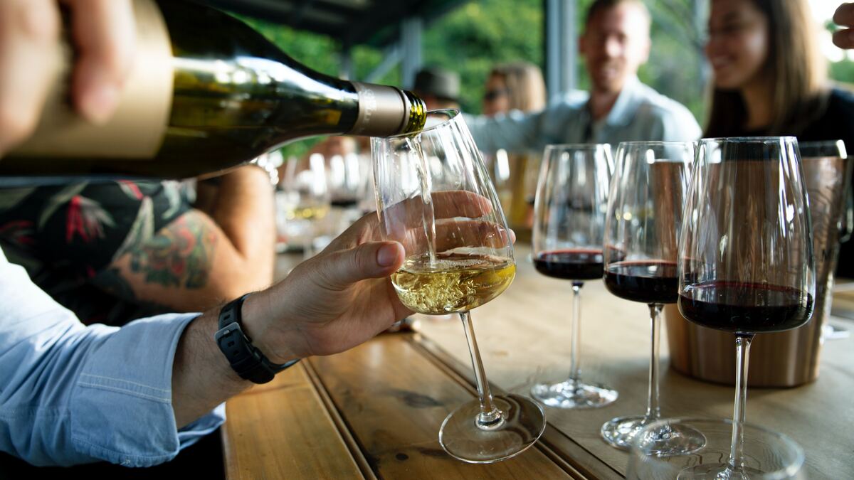 Pouring a glass of white wine on a bar with several other glasses of wine