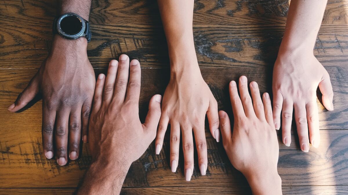 five hands coming together on a table