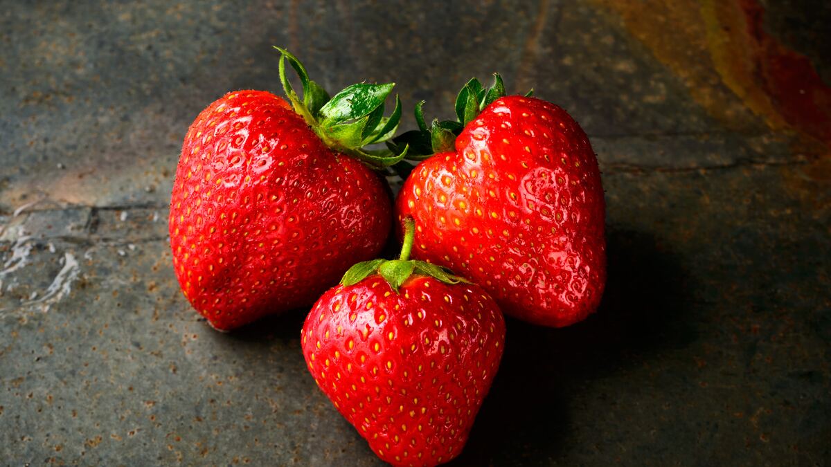 three strawberries on a stone